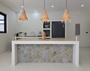cuisine ouverte moderne avec ilot central en pierre et suspensions lumineuses dans une villa a koh Samui