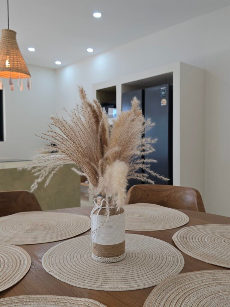 Ensemble de table à manger ronde avec des sets de table tissés et un vase rempli de pampas séchées comme centre de table