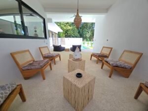 Espace de vie ouvert avec fauteuils modernes en bois et tables basses artisanales dans villa de luxe koh samui
