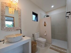 Salle de bain attenante moderne avec vasque en pierre, miroir en bois sculpte et douche a l'italienne a koh samui