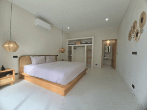 Suite parentale avec lit en bois, dressing intergre et vue sur la salle de bain privative a koh samui